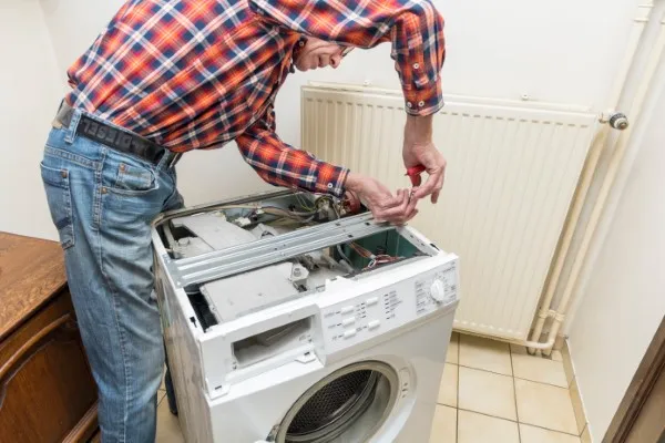 Hombre de mediana edad realizando una reparación de lavadoras, es un técnico profesional de reparación de lavadoras marca Maytag TITLE:reparación de lavadoras por un técnic