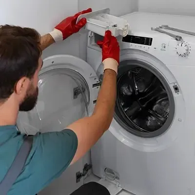 Tecnico de SERTEC revisando lavadora en el proceso de reparación de línea blanca