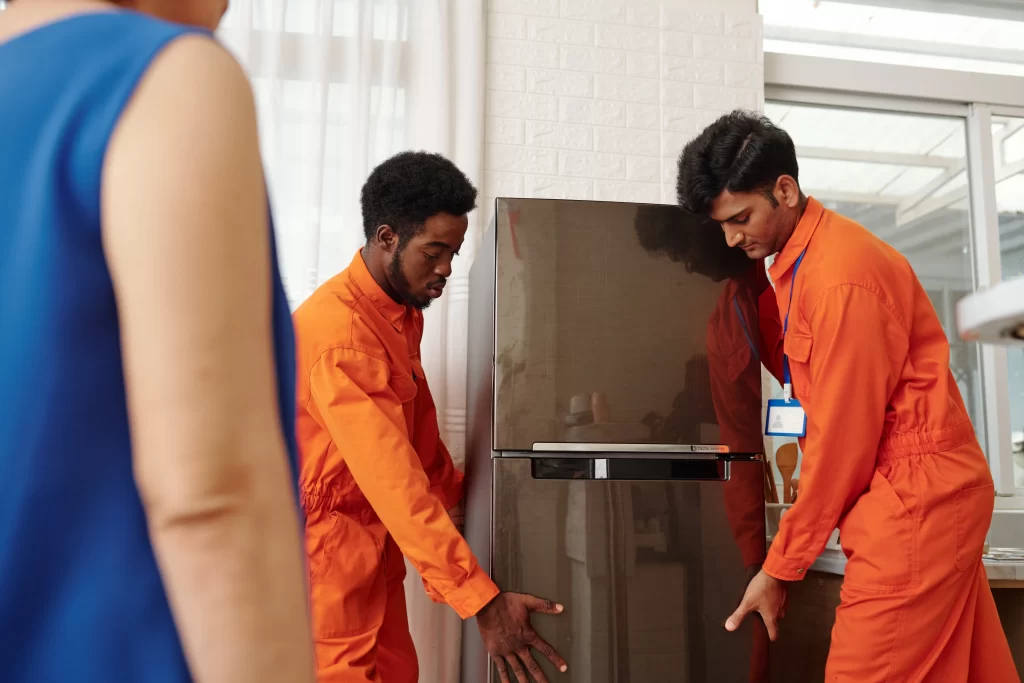 Dos técnicos SERTEC, cargando un refrigerador para realizar una inspección de fallas comunes en refrigeradores Samsung