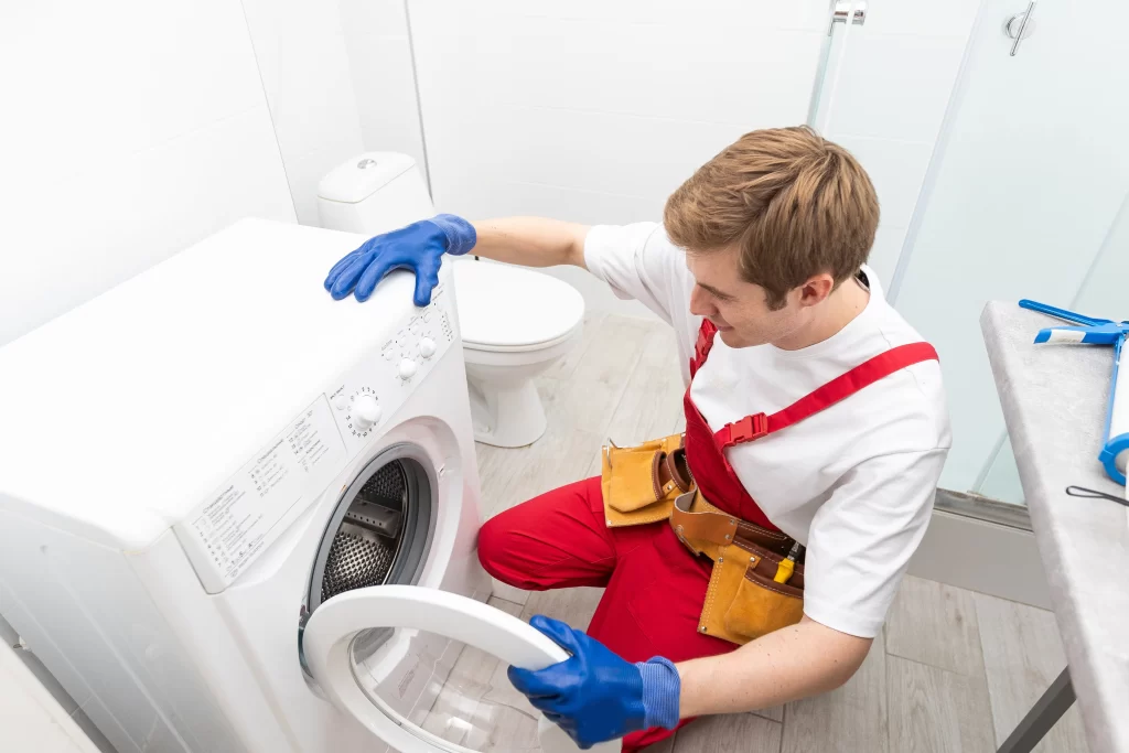 Hombre con overol rojo y guantes azules revisa errores más comunes en lavadoras LG Título: SERTEC resuelve los errores más comunes en lavadoras