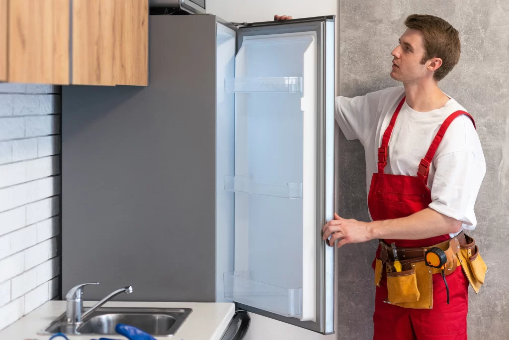 Técnico profesional de SERTEC con overol rojo y camisa blanca revisando fallas comunes en refrigeradores Samsung