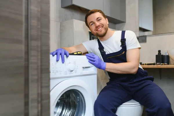 Técnico sonriente junto a una lavadora, listo para diagnosticar y reparar de forma experta cualquier fallo como el error LE LG.