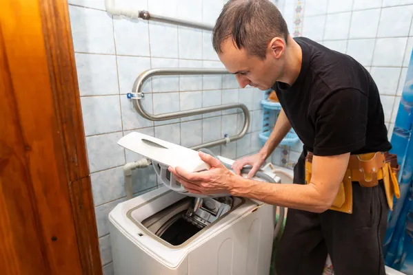 Técnico revisando el interior de una lavadora de carga superior para solucionar fallas comunes en lavadoras Samsung.